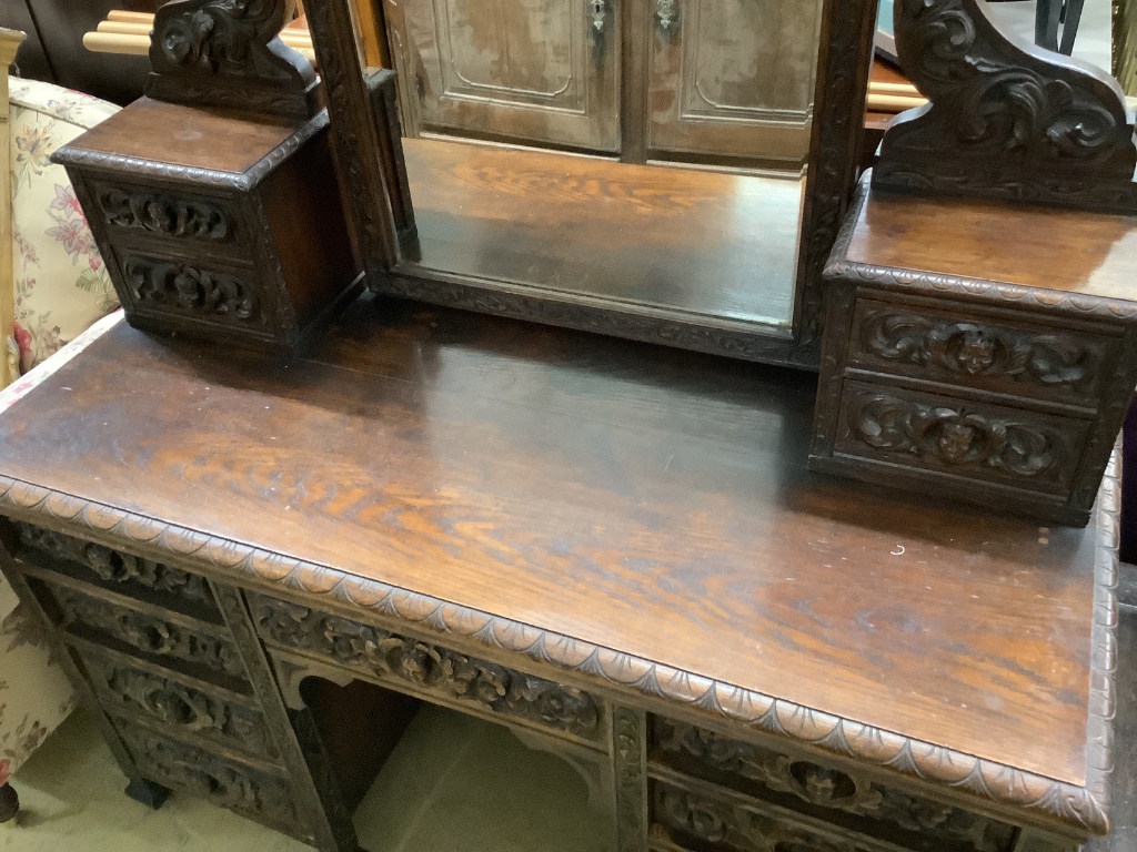 A late 19th century Flemish carveed oak kneehole dressing table, width 136cm depth 56cm height 183cm